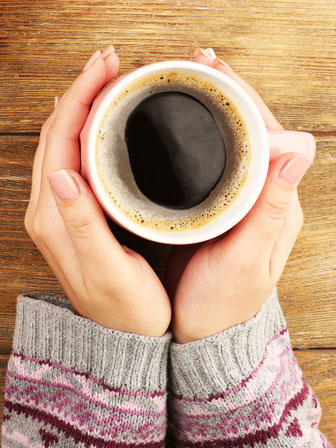 female hands holding a cup of coffee from below